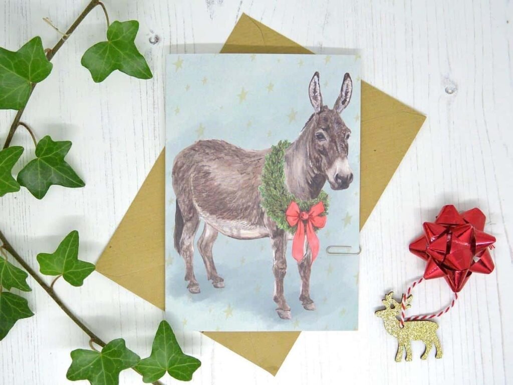 A cartoon donkey with reindeer antlers and a speech bubble saying, “Merry Ass-mas!